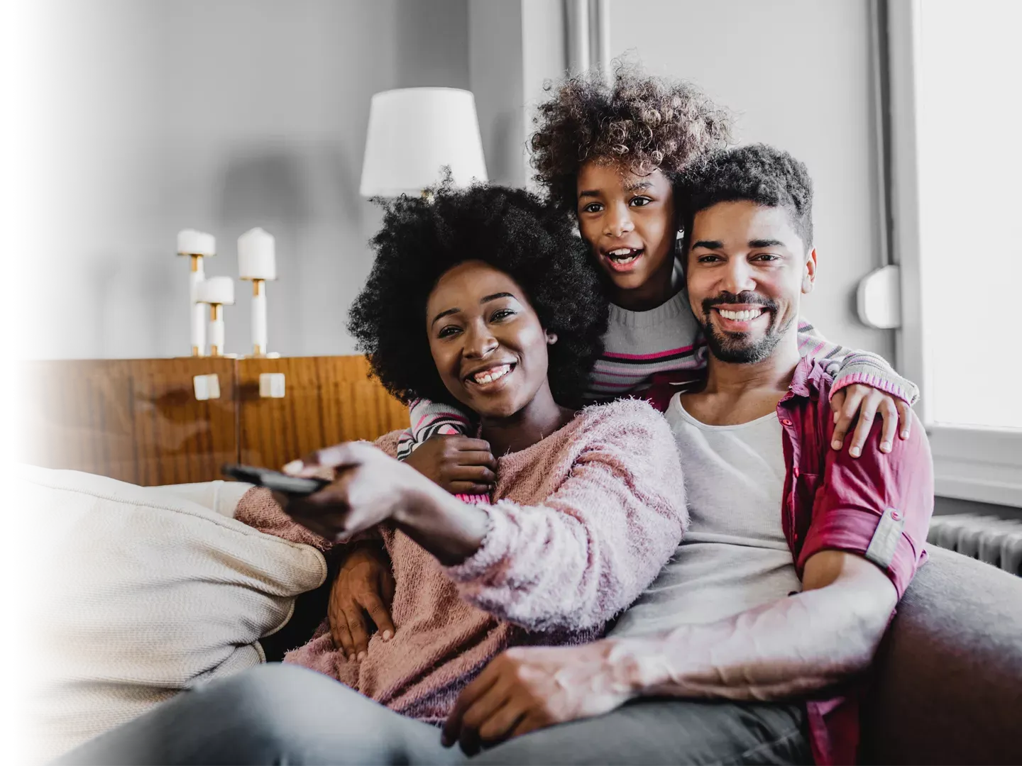 Cute family of 3 embracing, smiling, and enjoying their favorite show